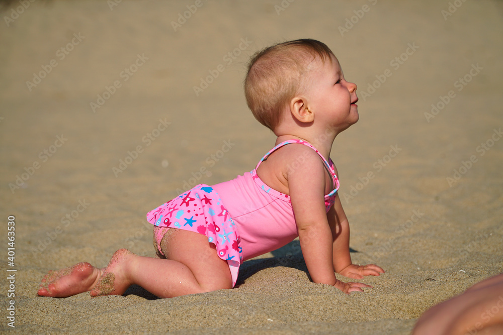 The kid learns to crawl. The child is crawling along the sand. First steps and first vacation. High quality photo The kid learns to crawl. The child is crawling along the sand. First steps and first vacation. High quality photo
