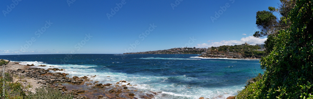 Stunning panoramic view of a deep blue sea and small beach from a coastal trail lookout, Sydney, New South Wales, Australia
