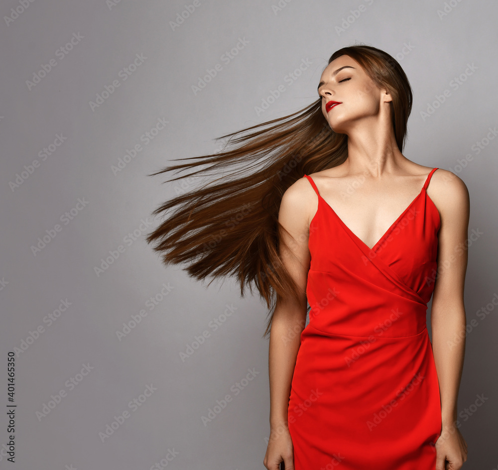 Young woman with long silky straight hair in red dress stands with ...