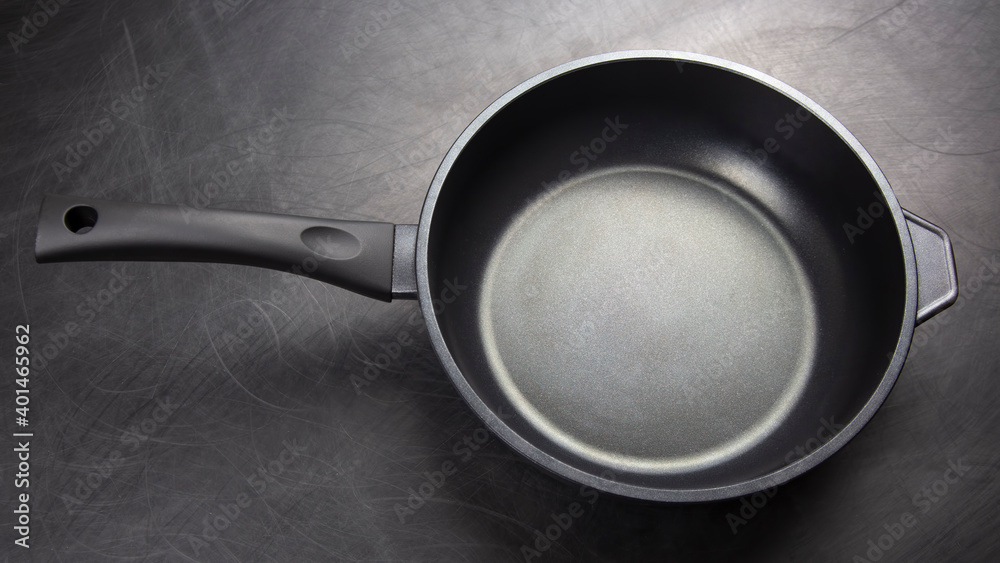 Black frying pan with non-stick teflon coating on dark background Black frying pan with non-stick teflon coating on dark background