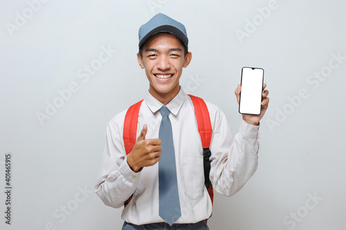 High School Student with uniform look at teh camera to showing white phone screen display to advertise something with thumb up