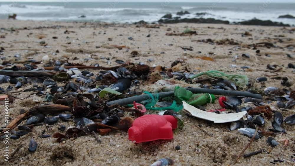 Plastic garbage washed up on beach. Low angle closeup. Shallow depth of field, slow motion. Plastic garbage washed up on beach. Low angle closeup. Shallow depth of field, slow motion.