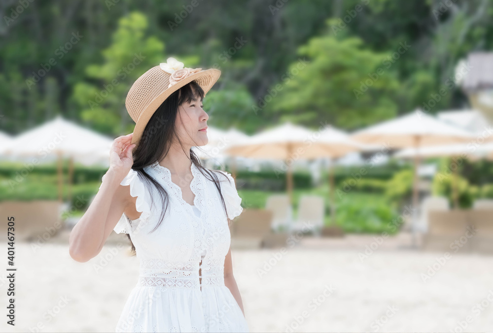 Asian woman with sea sand concept. lady standing with the wind blows my hair on blur image of white umbrella at  sea sand beach.  for in summer holiday or travel.