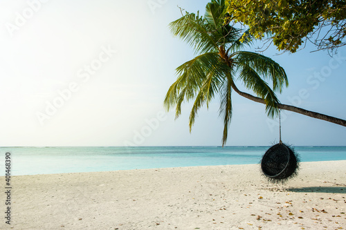 Tropical beach paradise as summer landscape with beach swing in shape of coconut or hammock and white sand. Luxury beach scene vacation summer holiday. Exotic island nature travel destination