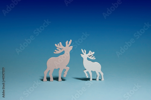 Horizontal conceptual studio subject photo with two wooden isolated deer toys of white and pink colours  looking to each other  on light blue gradient background