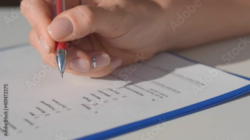 Woman puts a tick in the questionnaire with a red helium pen