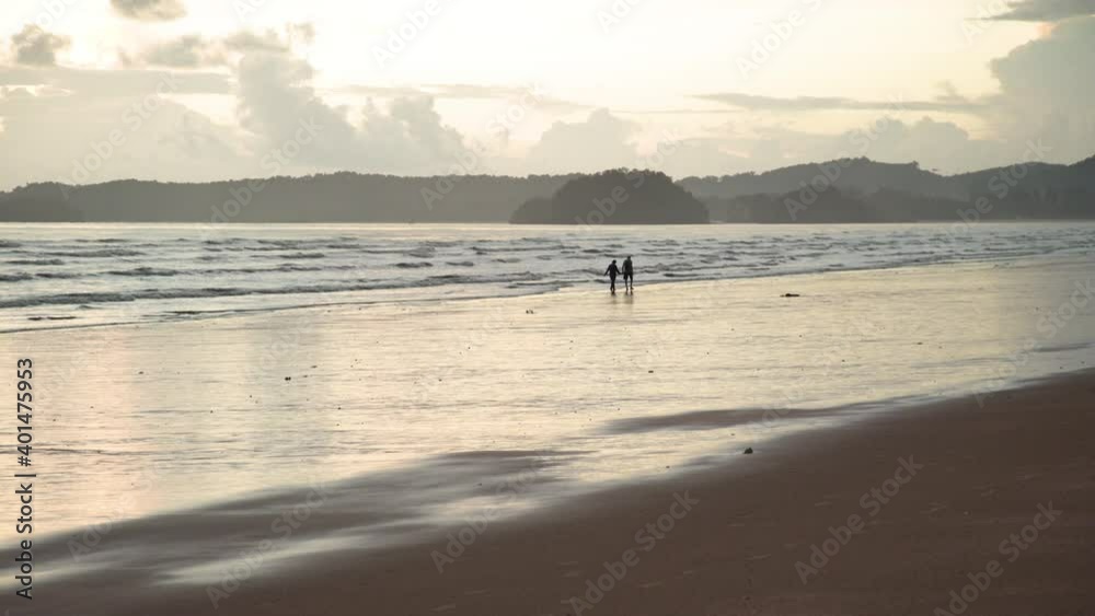 Tiny silhouette romantic couple on beach, cloudy sky on evening with mountain island landscape, empty space Tiny silhouette romantic couple on beach, cloudy sky on evening with mountain island landscape, empty space