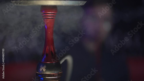 Close-up image of a part of a hookah with swirling smoke from it.
