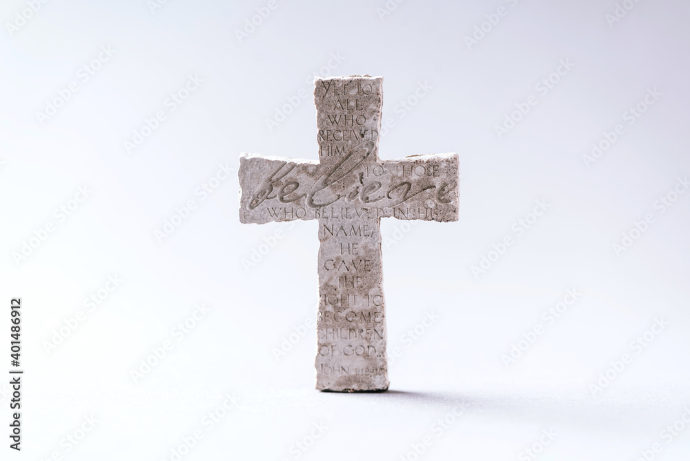Stone cross with inscription Believe on grey background, Copy space. Christian backdrop. Biblical faith, gospel, salvation concept