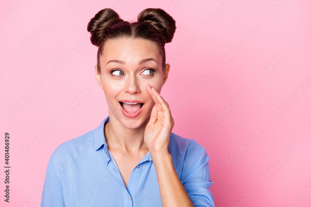 Photo portrait of smiling girl with top-knot rumoring telling secret looking empty space isolated on pastel pink color background Photo portrait of smiling girl with top-knot rumoring telling secret looking empty space isolated on pastel pink color background
