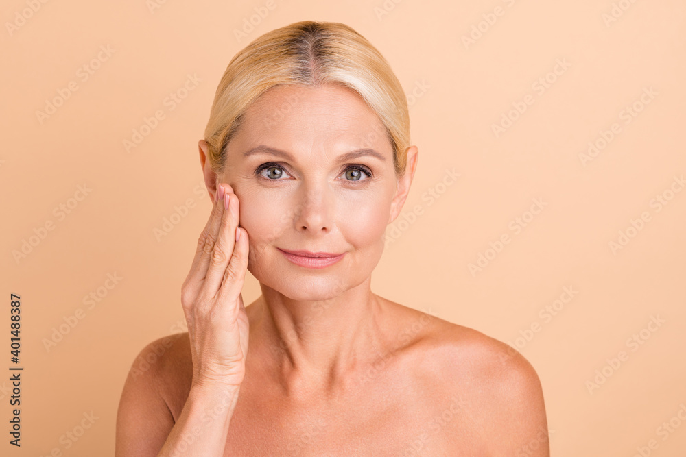 Photo of attractive aged lady nude shoulders perfect facial skin touch cheek isolated pastel beige color background Photo of attractive aged lady nude shoulders perfect facial skin touch cheek isolated pastel beige color background