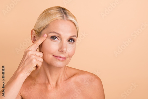Photo of natural beauty aged lady touch eyebrow line apply anti age cream uplift action isolated beige color background