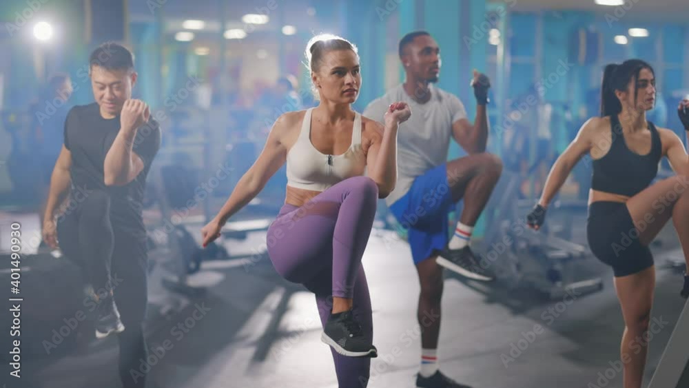 Diverse friendly attractive young people training out together warming-up muscles with cardiovascular exercise in the gym. Sports team. Multi-ethnic people.