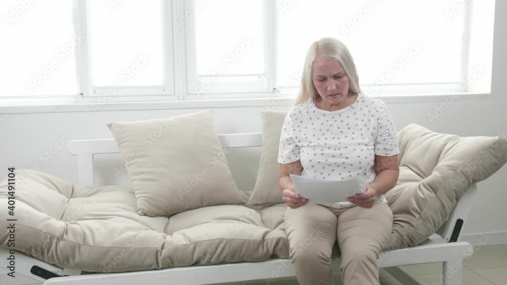 Stressed mature woman with results of her medical tests at home