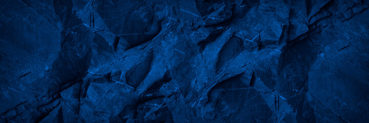 Abstract blue background. Toned monochrome stone rock texture background. Web banner. Wide. Dark blue rough surface background with space for design. Panoramic.