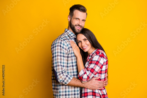 Photo portrait of happy spouses hugging isolated on vivid yellow colored background with blank space © deagreez