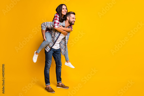 Photo portrait full body view of girl piggyback riding man isolated on vivid yellow colored background with blank space