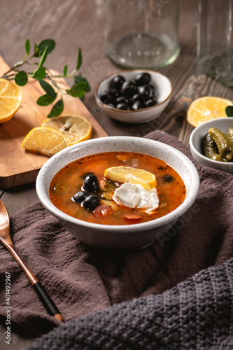 Traditional russian meat hodgepodge soup solyanka on rustic background