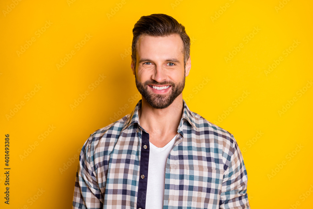 Portrait of attractive cheerful content bearded guy wearing checked shirt isolated over bright yellow color background Portrait of attractive cheerful content bearded guy wearing checked shirt isolated over bright yellow color background