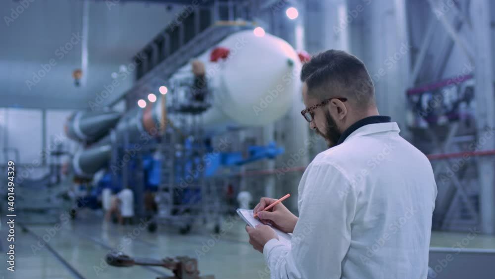 Industry 4 Concept: Man Engineer Makes Planning Technical Inspection of Future Project in Large Hangar. Vision Modern Industrial Design and Construction of Space or Aviation Transport Close-up Indoor Industry 4 Concept: Man Engineer Makes Planning Technical Inspection of Future Project in Large Hangar. Vision Modern Industrial Design and Construction of Space or Aviation Transport Close-up Indoor