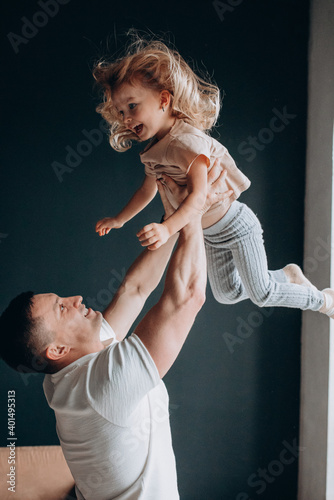 Happy father with his little daughter in his arms. Studio photography. Dark background.