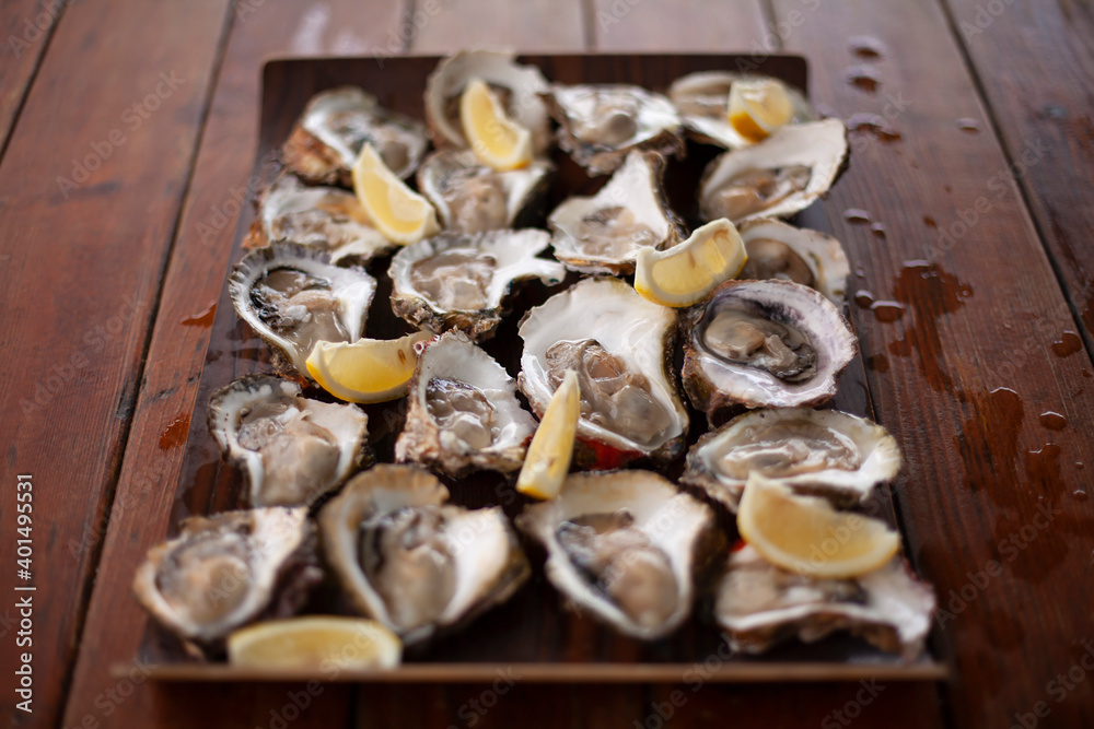 Fresh oysters with slices of lemon on the table. Fresh seafood. Fresh oysters with slices of lemon on the table. Fresh seafood.