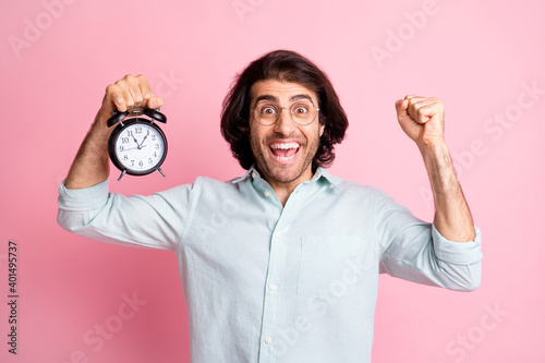 Photo of hooray funny guy hold clock hand fist wear spectacles blue shirt isolated on pastel pink color background © deagreez