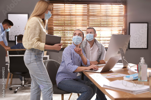 Coworkers with masks in office. Protective measure during COVID-19 pandemic