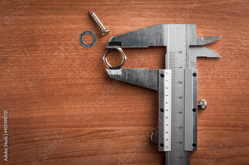 Vernier caliper used to measure the size of a bolt on a wooden table