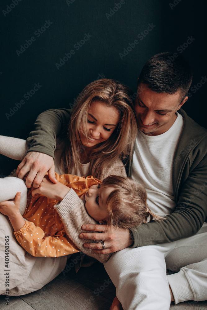 Photoshoot of a happy young family. Dad, mom and daughter. Studio photography.