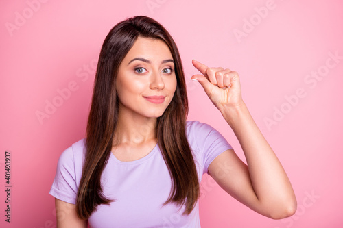Photo of smiling young lady showing measure gesture wear casual cloth isolated on pink color background