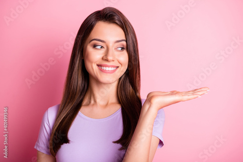 Photo portrait of beautiful woman looking at copyspace on hand smiling happily isolated on pastel pink color background