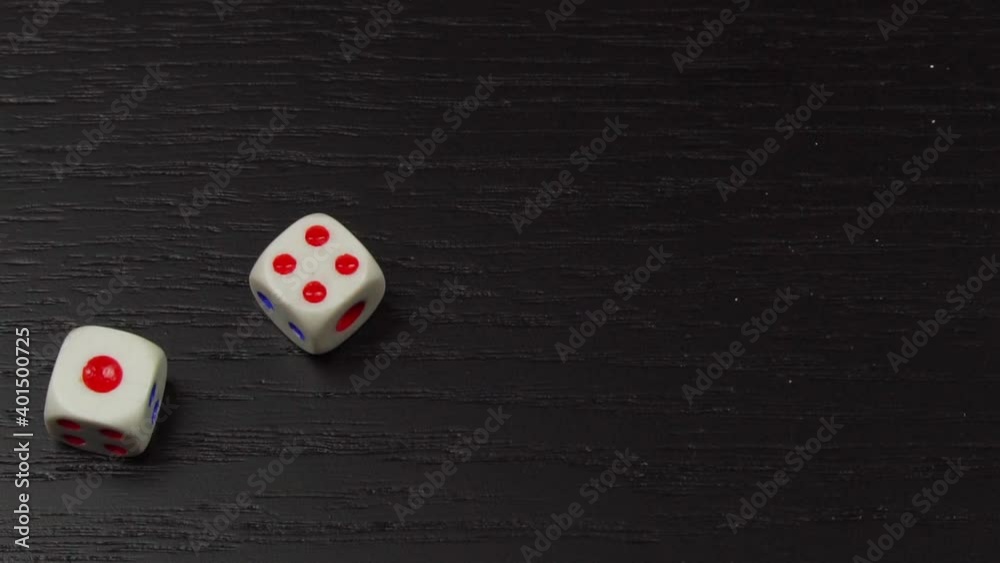The Concept Of An Entertaining Game. The hand rolls the dice on the black wooden table. Close-up of rotating bones and fingers. drops 4