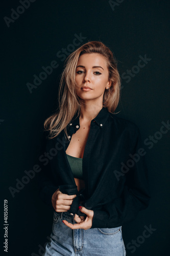 Photoshoot of a blonde in a black bra and jeans. Studio photography.