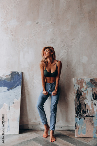 Photoshoot of a blonde in a black bra and jeans. Studio photography.