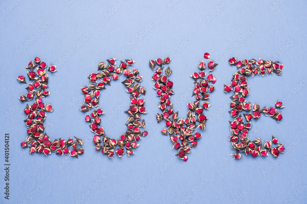 Inscription Love made from dried rose flowers on blue background. Congratulations on Valentine's Day