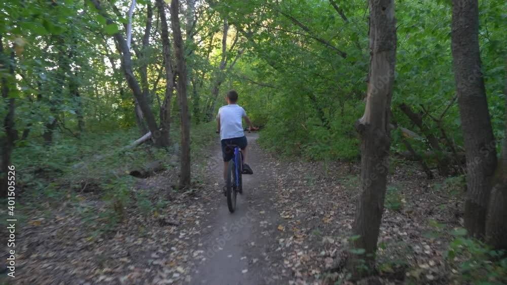 A happy child rides a bicycle in a park in the open air. Cycling on a path in the woods. Active rest of the child. Healthy lifestyle, children's sports. A happy child rides a bicycle in a park in the open air. Cycling on a path in the woods. Active rest of the child. Healthy lifestyle, children's sports.