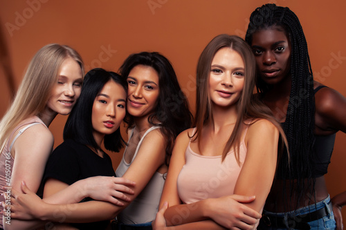 young pretty asian, caucasian, afro woman posing cheerful together on brown background, lifestyle diverse nationality people concept