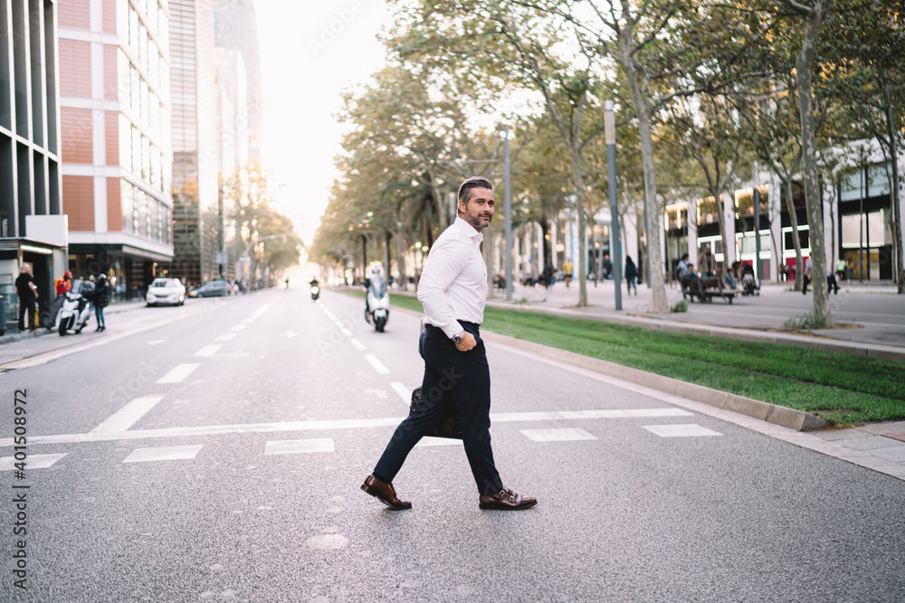 Middle aged Caucasian businessman 40 years old in white shirt crossing road in metropolitan downtown, mature male banker with briefcase walking in financial district getting to meeting destination Middle aged Caucasian businessman 40 years old in white shirt crossing road in metropolitan downtown, mature male banker with briefcase walking in financial district getting to meeting destination