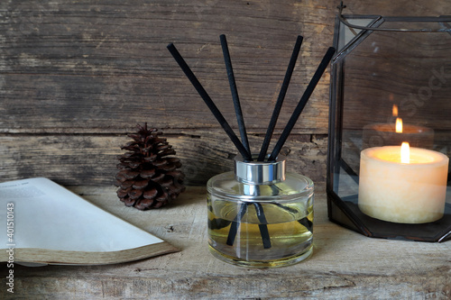 nice aromatic scented reed diffuser air freshener bottle is on the wooden table with scented candle and background of old vintage wooden texture wall of the living room in cottage for christmas day
