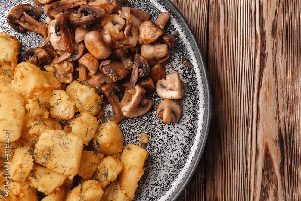 Fototapeta premium Fried potatoes near fried mushrooms on a gray plate top view, close-up