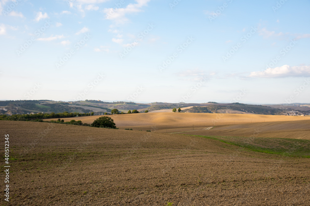 It is the scenery near Pienza in Tuscany, Italy. Agricultural land spreads out on the hill under the blue sky.