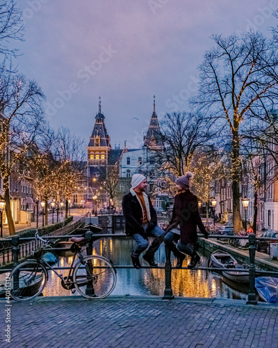Photography couple on city trip Amsterdam Netherlands canals with Christmas lights during December, canal historical center of Amsterdam at night
