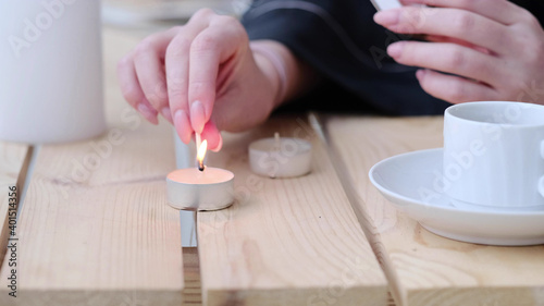 womens hand lighting the candle. selective focus. Cozy flatlay with wooden tray  cup of coffee or cocoa