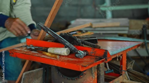 Wallpaper Mural Old master with wrinkled hands saws a wooden board with a hand saw on wood in the workshop Torontodigital.ca