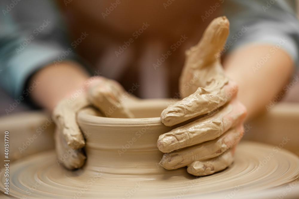 Woman working on the potter's wheel. Artisan making a cup from clay pot. Workshop of handmade modeling on the potters wheel.