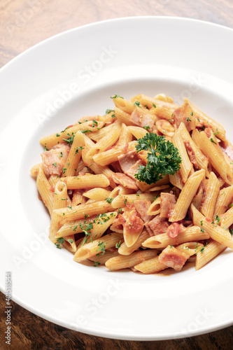 penne amatriciana tomato and ham sauce pasta on wood table