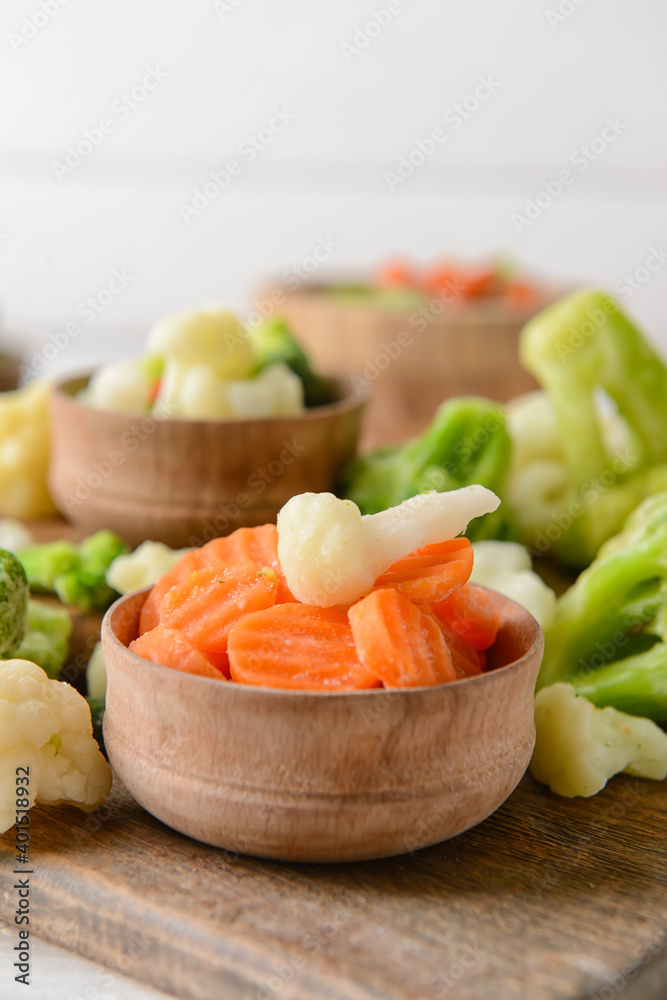 Frozen vegetables in bowls on light background Frozen vegetables in bowls on light background