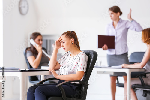 Stressed woman with headache and noisy people in office photo