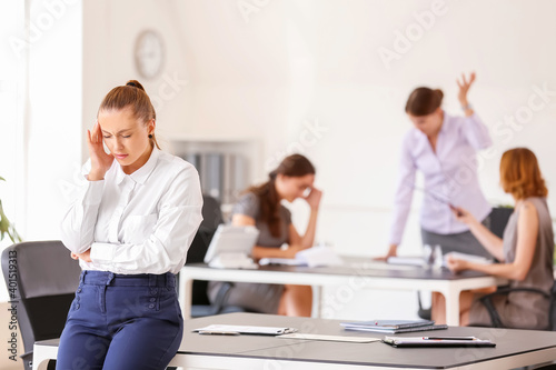 Stressed woman with headache and noisy people in office